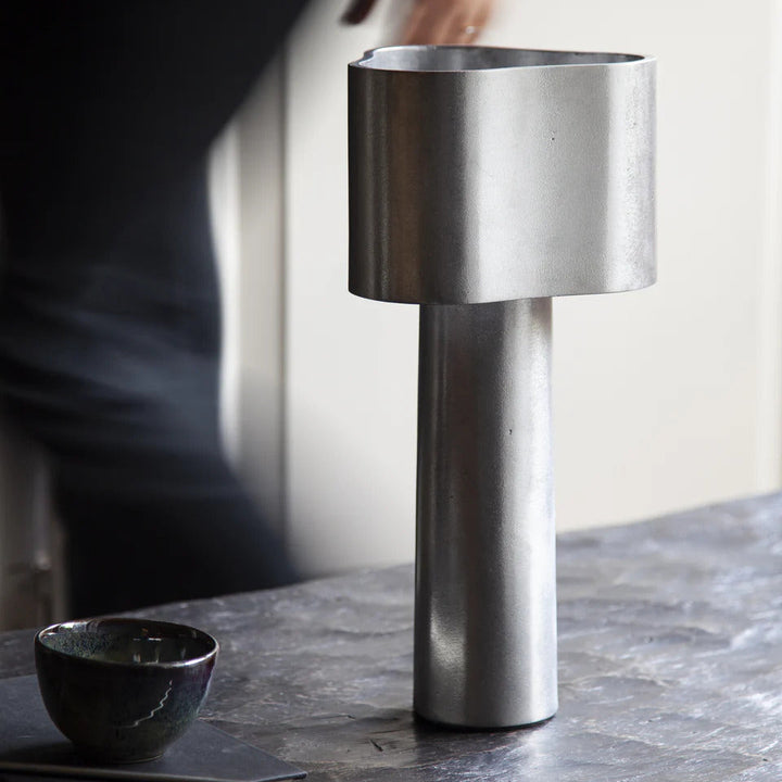 Metallic table lamp on a dark surface with a blurred background