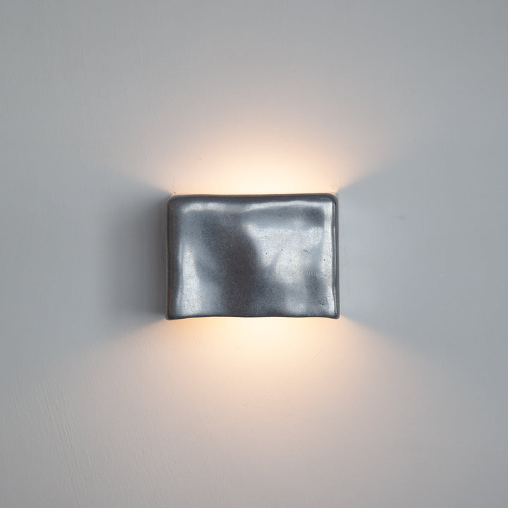 Metallic wall light by Stem Design on a light grey background