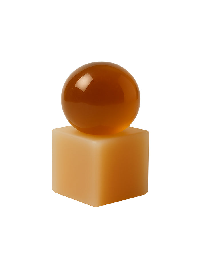 Brown sphere soap on a beige rectangular block against a white background
