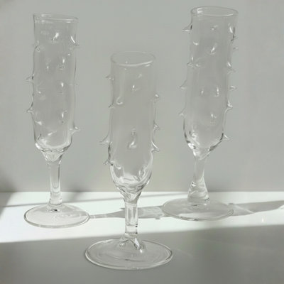 Three clear glass champagne flutes with textured design on a light gray background