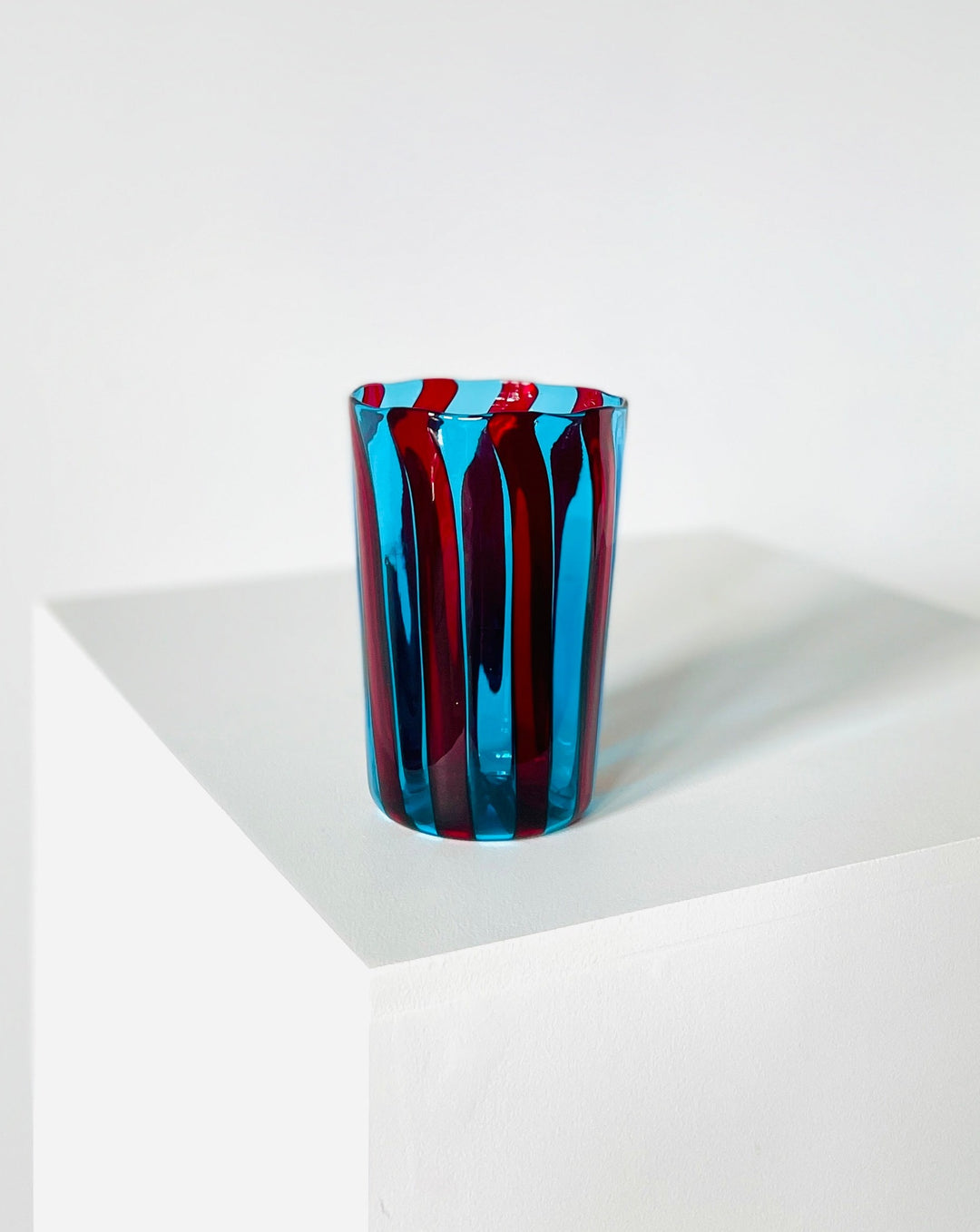 Striped blue and red drinking glass by Shop Dessein Parke, displayed on a white surface.