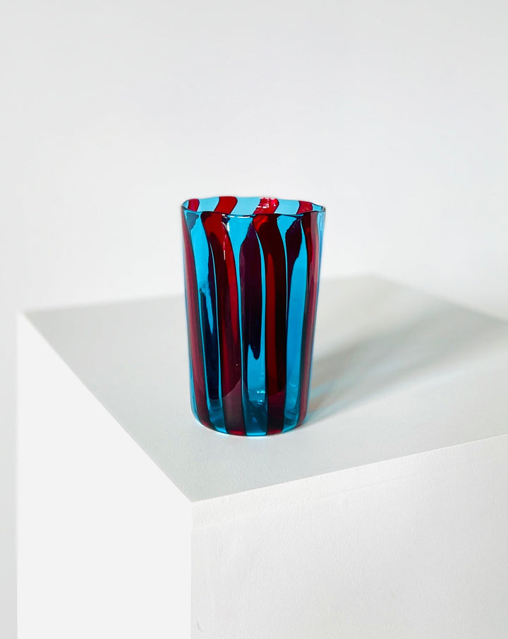 Striped blue and red drinking glass by Shop Dessein Parke, displayed on a white surface.
