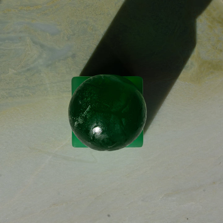 Green sphere soap on a green resin square block against a white background