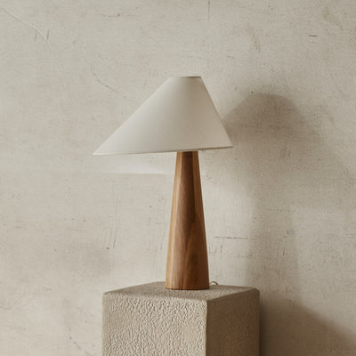 Table lamp with wooden base and white shade on a textured surface