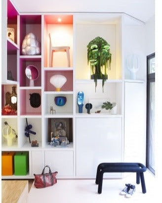 Forest green bench by Moustache Paris, with a unique looped design, positioned indoors with nearby shelving.