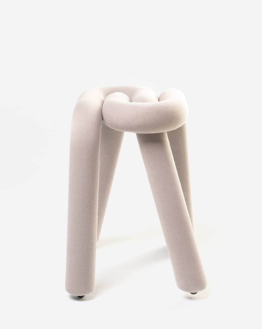 Upholstered grey stool by Moustache with a knot-shaped seat and four legs on a white background.