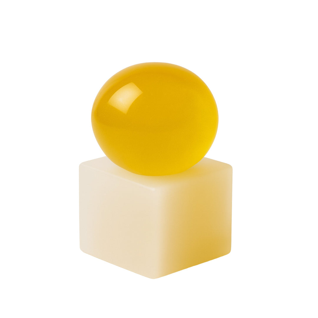 Yellow sphere soap on a yellow resin cube against a white background