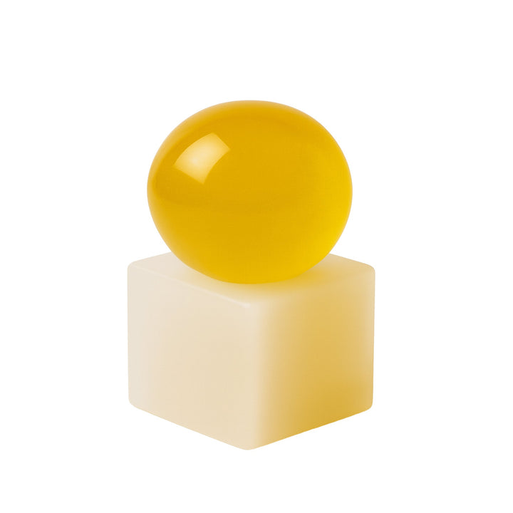 Yellow sphere soap on a yellow resin cube against a white background