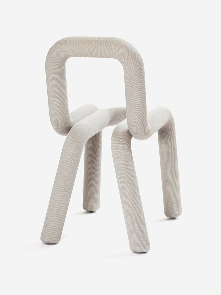 Light gray chair by Moustache Paris with a rounded tubular frame and fabric covering.