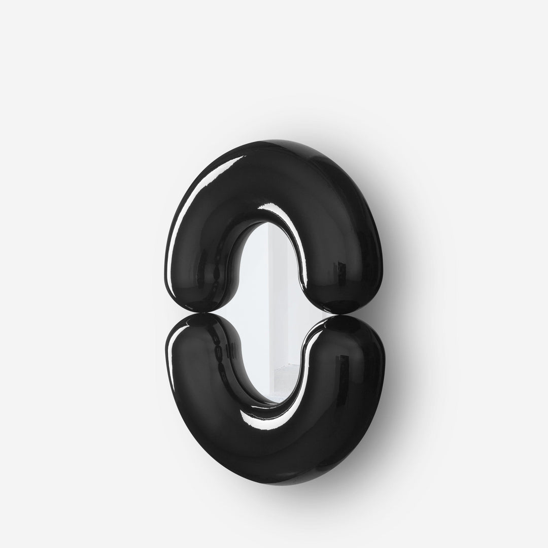 Black wall mirror by Moustache Paris with rounded form, and a glossy finish reflecting surface below.
