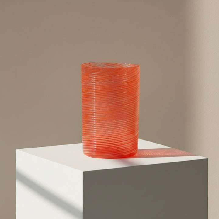 Orange textured vase on a white pedestal against a beige background