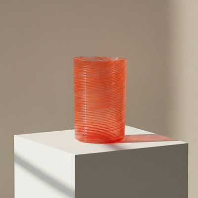 Orange textured vase on a white pedestal against a beige background