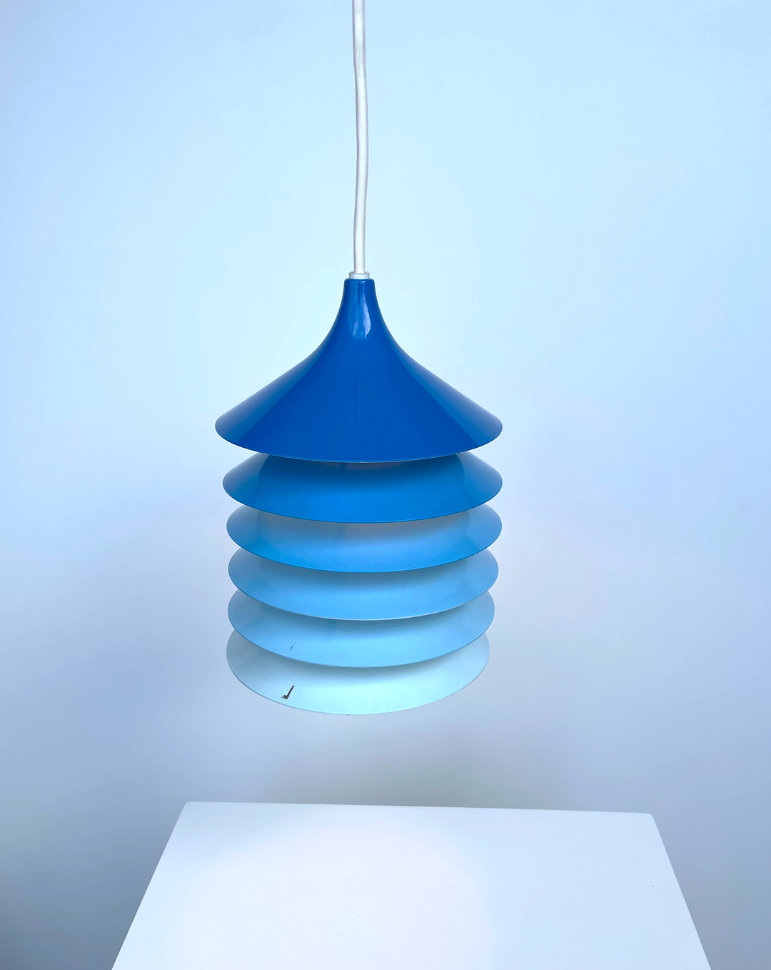 Blue pendant light by IKEA, with tiered shade in an ombre effect, and a white cord.