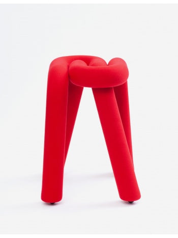 Red stool by Moustache Paris with a knot-like seat and tubular legs, on a white background.
